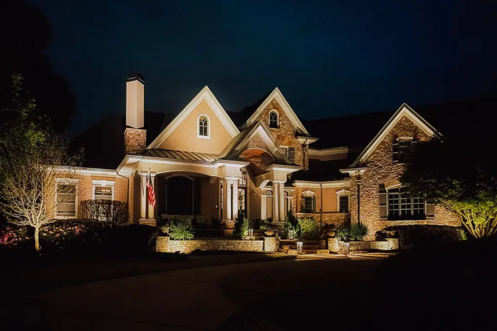 landscape lighting how to design Guide - Image of a brick home illuminated at night with landscape Lighting.